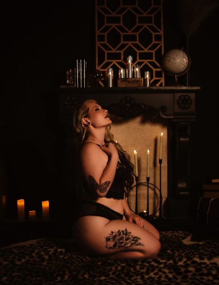 A woman touches her chest as she poses in lingerie in Boudoir photo studio-Love to the Moon Photography during her boudoir photo session near St. Louis Missouri.