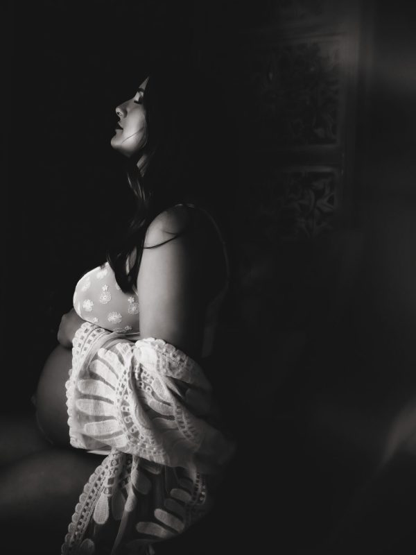 A pregnant woman poses in a black-and-white image.