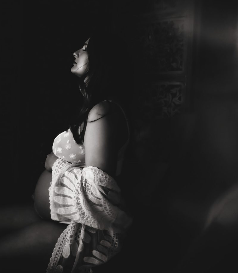 A pregnant woman poses in a black-and-white image.